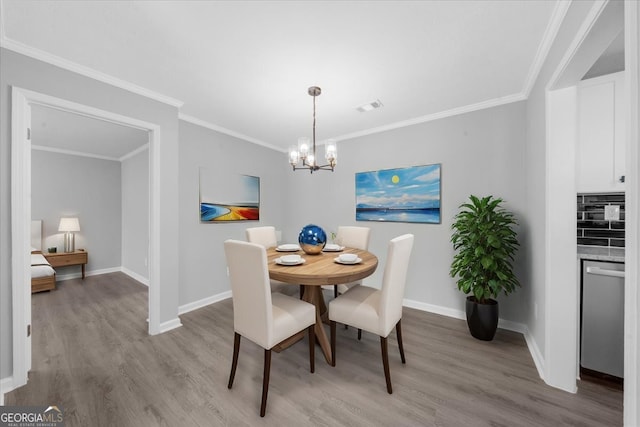 dining room featuring crown molding, a chandelier, and light hardwood / wood-style flooring