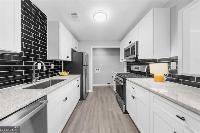 kitchen featuring white cabinetry, sink, light stone counters, and stainless steel appliances