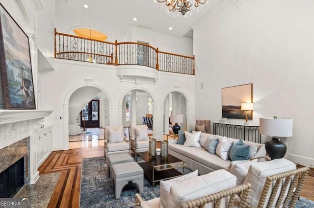 living room featuring an inviting chandelier, ornamental molding, wood-type flooring, and a fireplace