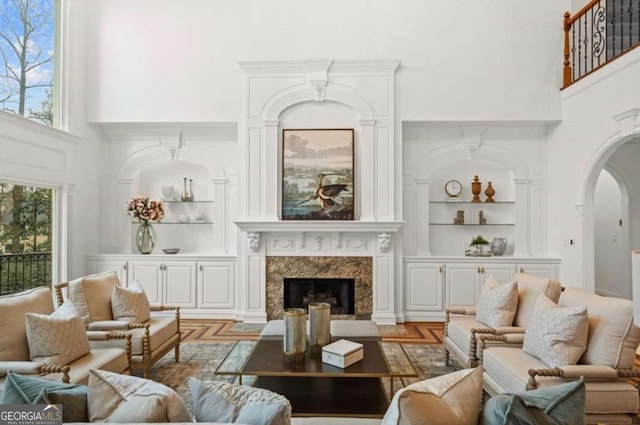 living room featuring a high ceiling, a fireplace, and built in shelves