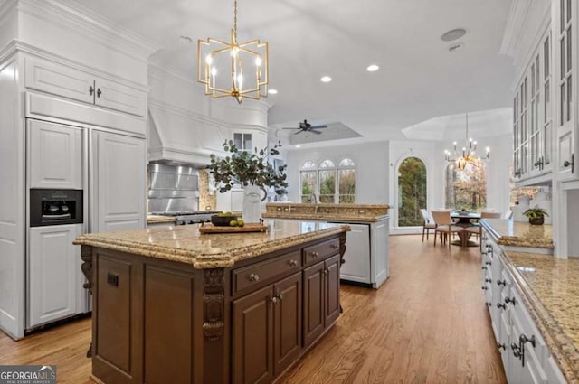 kitchen with white cabinets, hanging light fixtures, a center island, paneled built in fridge, and dark brown cabinetry