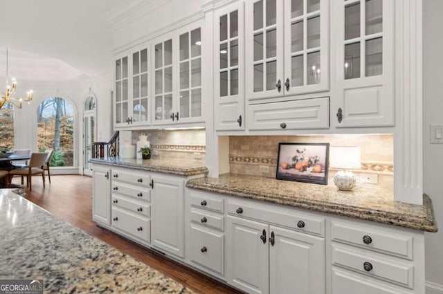 bar featuring white cabinetry, crown molding, light stone countertops, and an inviting chandelier