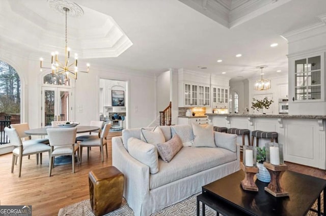 living room featuring ornamental molding, light wood-type flooring, and a chandelier