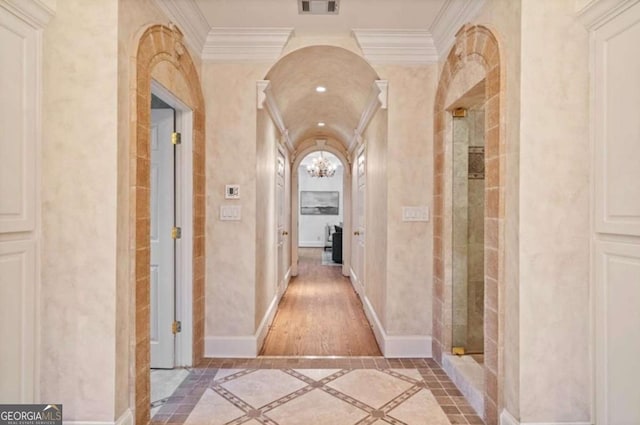 hallway with ornamental molding and a notable chandelier