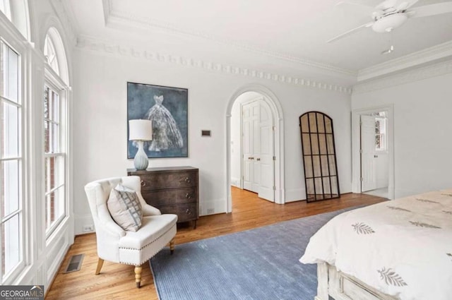 bedroom with hardwood / wood-style flooring, crown molding, ceiling fan, and a tray ceiling