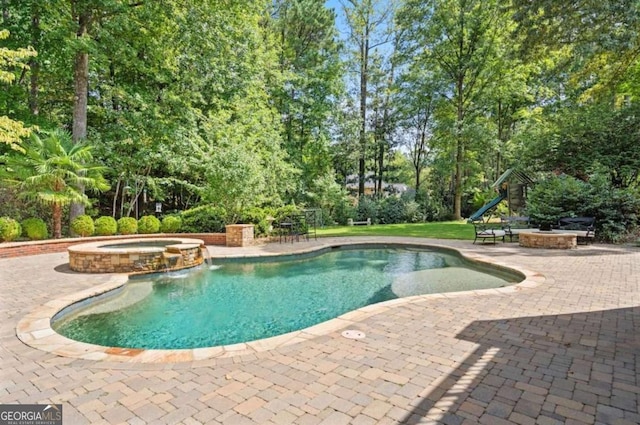 view of swimming pool with a fire pit, a patio, pool water feature, and an in ground hot tub