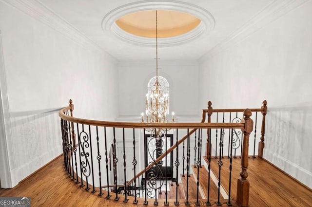 stairs featuring a tray ceiling, crown molding, wood-type flooring, and a chandelier