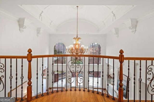 hall featuring hardwood / wood-style flooring, ornamental molding, lofted ceiling, and a chandelier