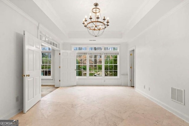 empty room featuring crown molding, a raised ceiling, and a chandelier