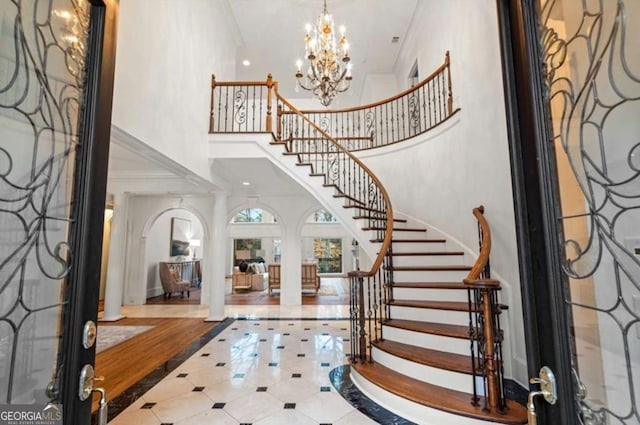 foyer entrance with an inviting chandelier, a towering ceiling, and ornamental molding