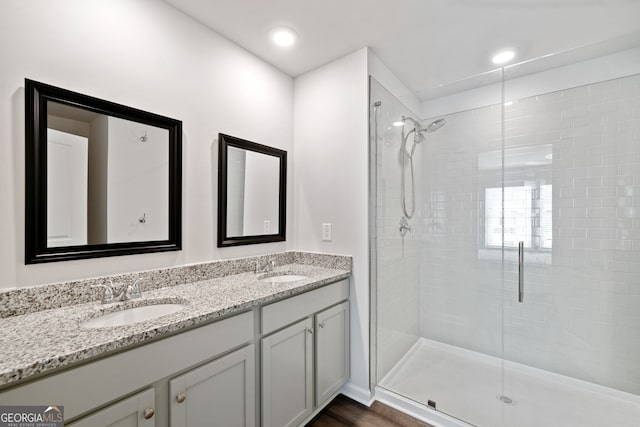 bathroom with hardwood / wood-style flooring, vanity, and a shower with door