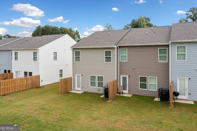 rear view of property with a lawn and central air condition unit