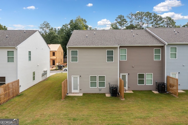 rear view of house with cooling unit and a yard