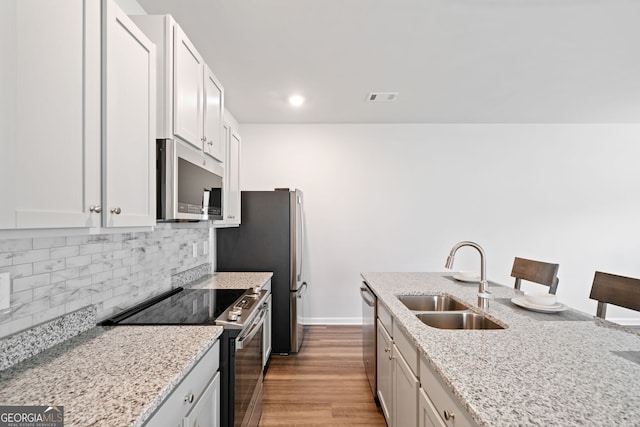 kitchen with sink, appliances with stainless steel finishes, white cabinetry, and light stone counters