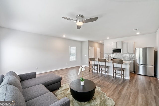 living room with ceiling fan, wood-type flooring, and sink