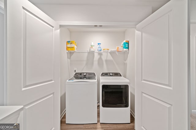 clothes washing area with separate washer and dryer and wood-type flooring