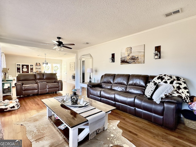 living room with ceiling fan, hardwood / wood-style flooring, crown molding, and a textured ceiling