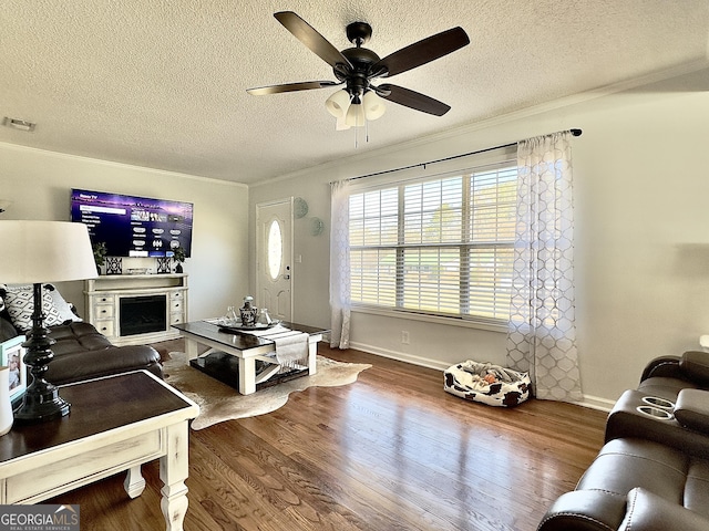 living room featuring a textured ceiling, ornamental molding, hardwood / wood-style floors, and ceiling fan