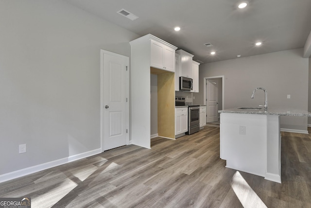 kitchen with visible vents, wood finished floors, white cabinets, a sink, and stainless steel appliances