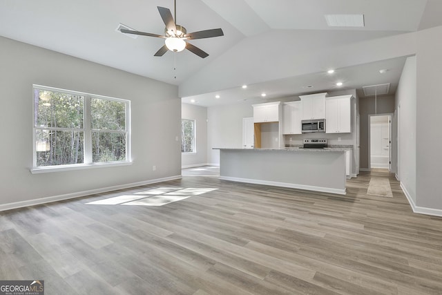unfurnished living room with attic access, high vaulted ceiling, light wood-type flooring, recessed lighting, and a ceiling fan