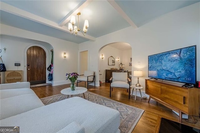 living room featuring beamed ceiling, hardwood / wood-style flooring, and a notable chandelier