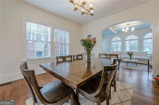 dining room with plenty of natural light, dark wood-type flooring, and an inviting chandelier