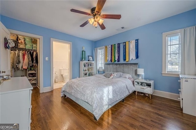 bedroom featuring connected bathroom, dark hardwood / wood-style flooring, a spacious closet, ceiling fan, and a closet