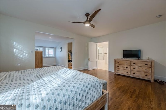 bedroom with ensuite bathroom, dark hardwood / wood-style floors, ceiling fan, and a spacious closet