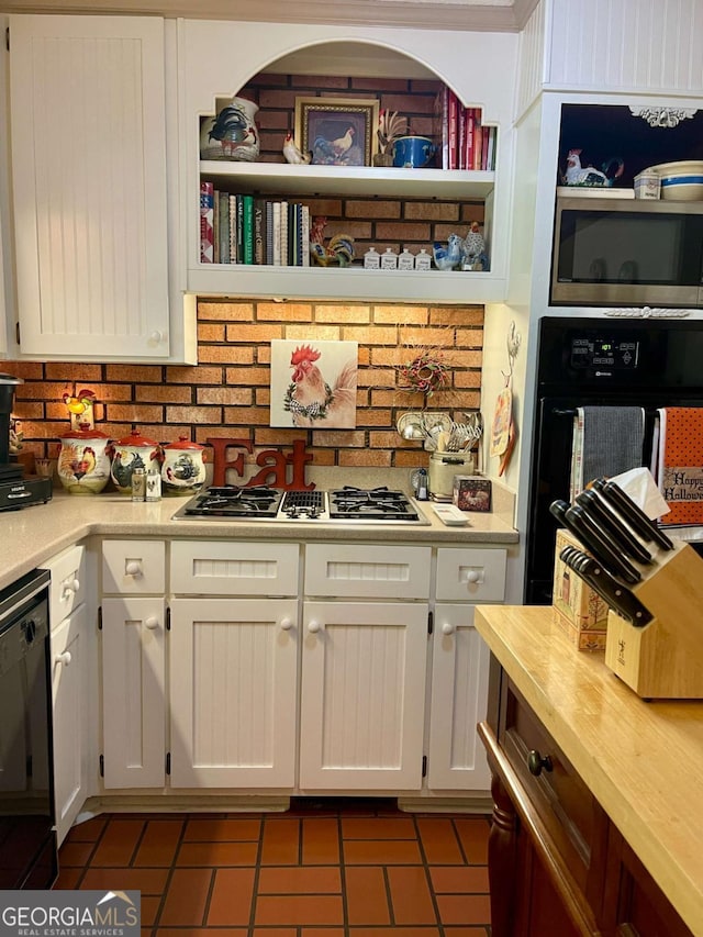 kitchen with white cabinetry, dark tile patterned floors, and black appliances