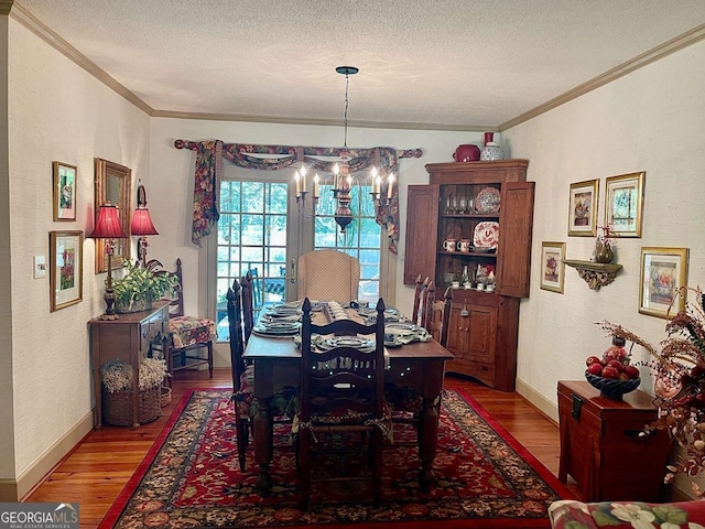 dining area with hardwood / wood-style floors, a notable chandelier, ornamental molding, and a textured ceiling