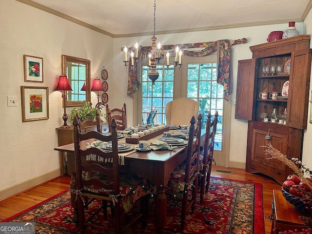 dining area featuring an inviting chandelier, wood-type flooring, and ornamental molding