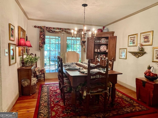 dining space featuring crown molding, an inviting chandelier, and light hardwood / wood-style flooring