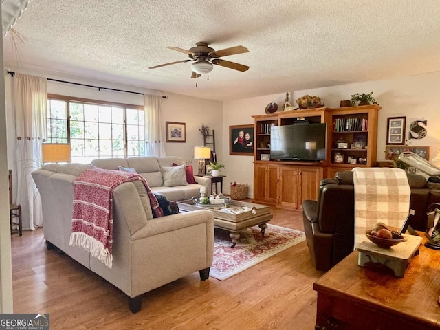 living room with ceiling fan, a textured ceiling, and light wood-type flooring