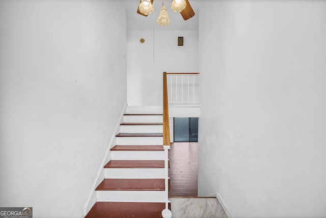 stairway with ceiling fan and wood-type flooring