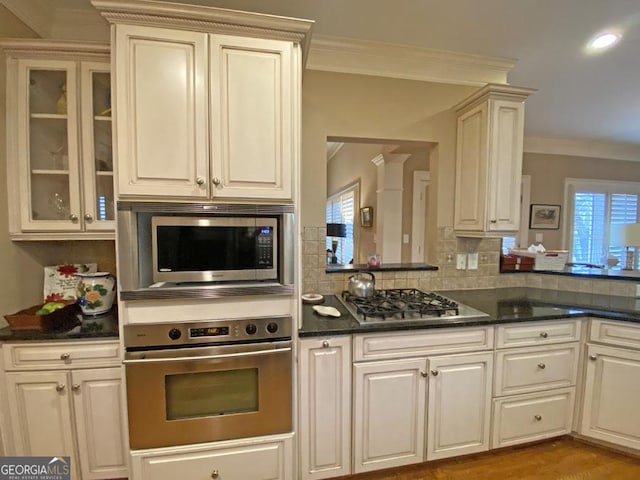 kitchen featuring hardwood / wood-style floors, decorative backsplash, ornamental molding, and stainless steel appliances