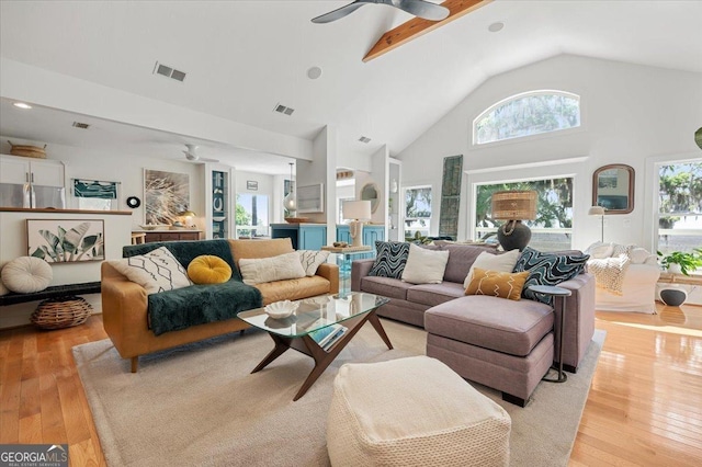 living area with light wood-type flooring, high vaulted ceiling, visible vents, and a ceiling fan