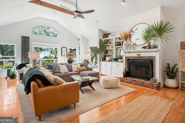 living area with high vaulted ceiling, light wood finished floors, and a fireplace