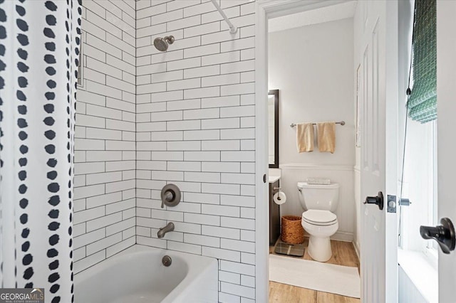 full bathroom featuring toilet, a wainscoted wall, wood finished floors, and shower / tub combo with curtain