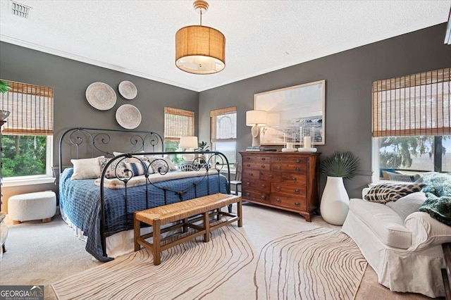 bedroom with ornamental molding, light colored carpet, visible vents, and a textured ceiling