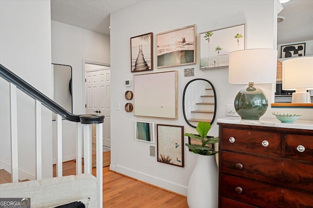 interior space with light wood-style flooring, a textured ceiling, and baseboards