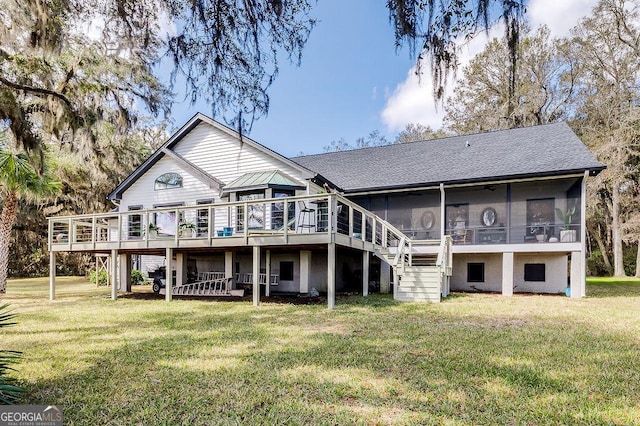 rear view of property featuring a deck, a sunroom, a yard, roof with shingles, and stairway