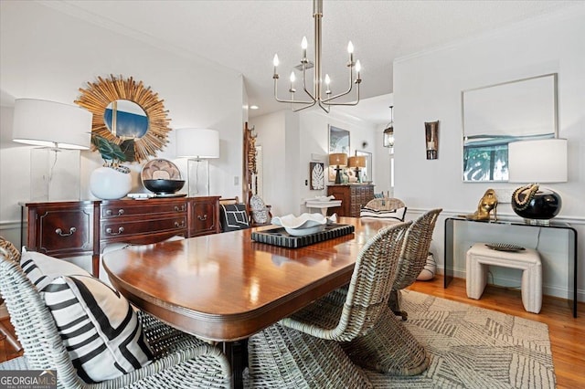 dining space with baseboards, light wood-style floors, an inviting chandelier, and crown molding