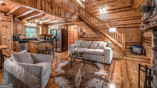 living room featuring a high ceiling, wood ceiling, wooden walls, and light hardwood / wood-style flooring