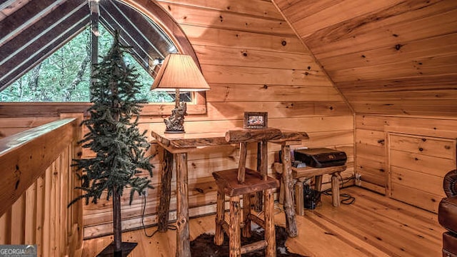 office space with lofted ceiling, hardwood / wood-style flooring, and wooden walls