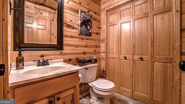 bathroom featuring vanity, wooden walls, and toilet