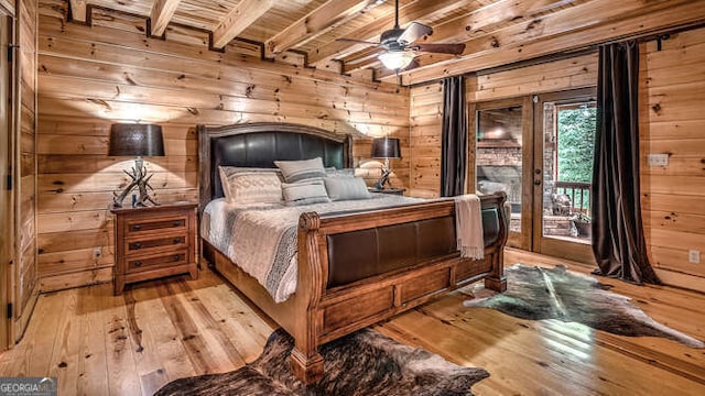 bedroom with beam ceiling, wooden walls, wooden ceiling, and light hardwood / wood-style floors