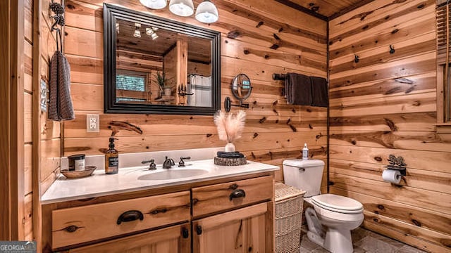 bathroom featuring toilet, vanity, and wooden walls