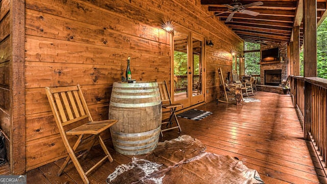 wooden terrace with ceiling fan and an outdoor stone fireplace