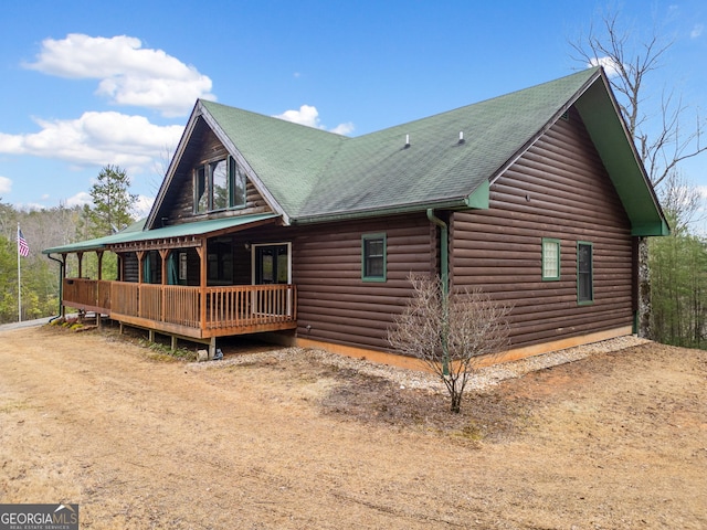 exterior space featuring dirt driveway and roof with shingles