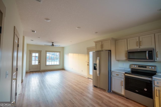 kitchen featuring ceiling fan, appliances with stainless steel finishes, a textured ceiling, and light hardwood / wood-style flooring